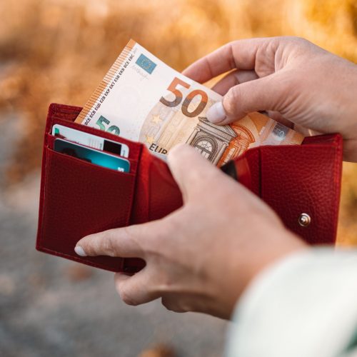 Close up of business woman hands holding a red leather wallet with 50 euro banknotes